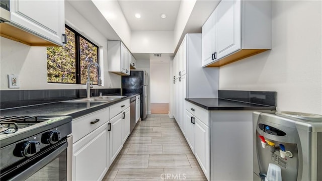 kitchen with white cabinets, stainless steel dishwasher, black range, and sink