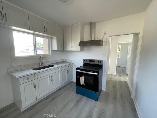 kitchen featuring sink, wall chimney exhaust hood, electric range oven, white cabinets, and light wood-type flooring