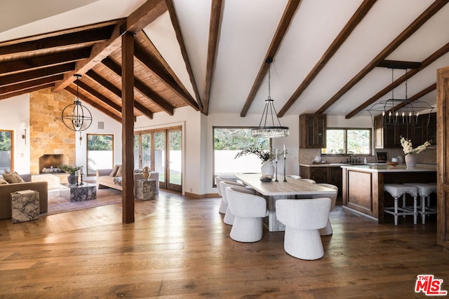 dining area featuring a stone fireplace, dark hardwood / wood-style flooring, beamed ceiling, high vaulted ceiling, and a notable chandelier