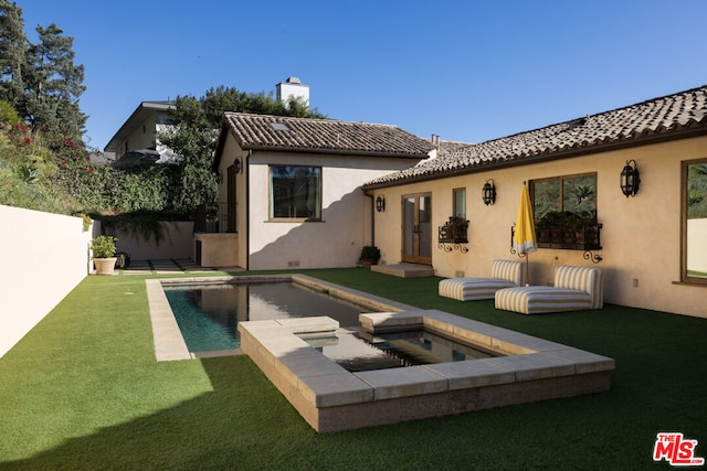 rear view of house featuring a yard and a swimming pool with hot tub