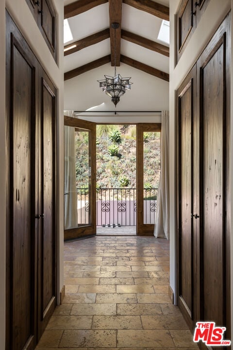 doorway featuring beam ceiling, high vaulted ceiling, and a notable chandelier