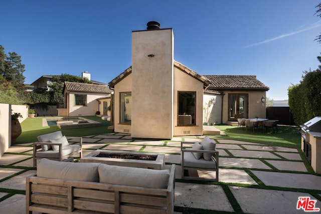 back of property featuring a patio area and an outdoor living space with a fire pit