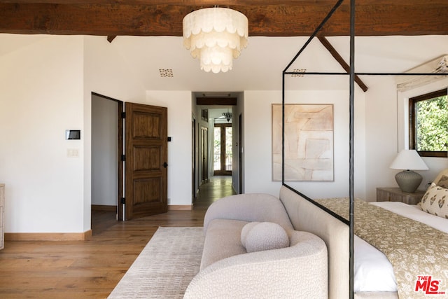 bedroom featuring hardwood / wood-style floors, beamed ceiling, and a chandelier