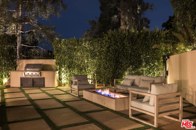 patio at twilight with grilling area, exterior kitchen, and an outdoor fire pit