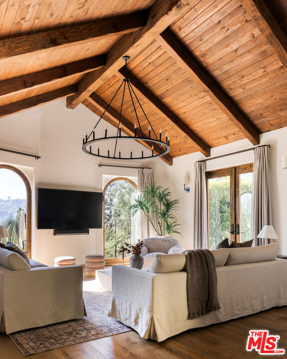 living room with lofted ceiling with beams, french doors, a healthy amount of sunlight, and hardwood / wood-style flooring