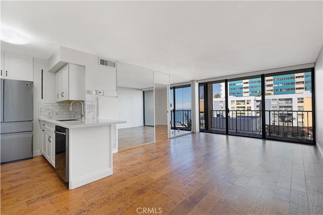 kitchen featuring sink, stainless steel appliances, white cabinetry, and light hardwood / wood-style flooring