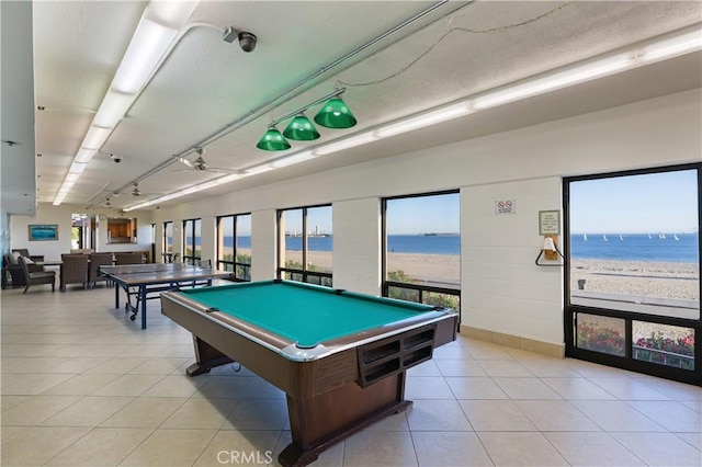 rec room featuring ceiling fan, a view of the beach, light tile patterned floors, a water view, and billiards