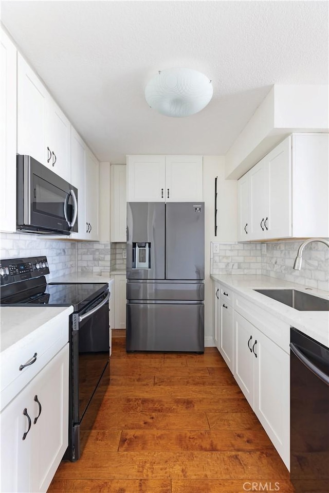 kitchen with black appliances, white cabinets, sink, dark hardwood / wood-style floors, and decorative backsplash