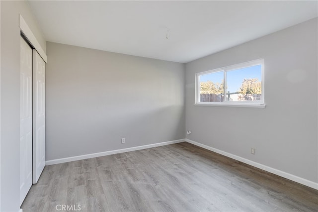 unfurnished bedroom featuring light hardwood / wood-style flooring and a closet