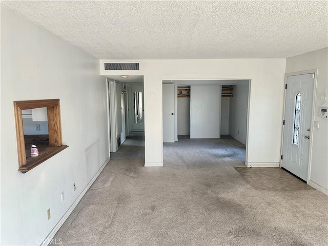 carpeted empty room featuring a textured ceiling