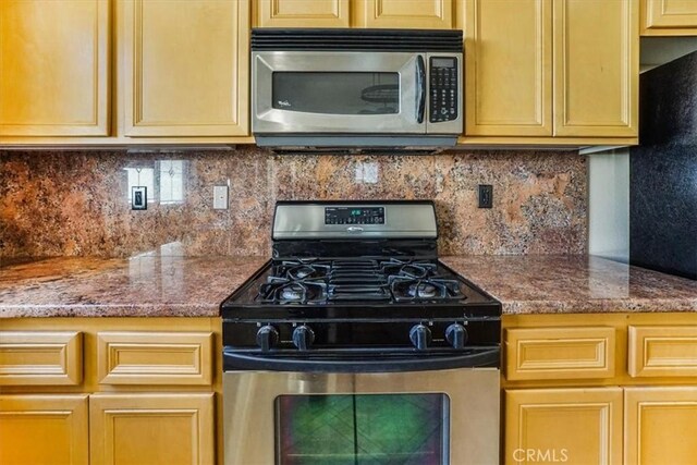 kitchen with backsplash, light stone counters, and stainless steel appliances