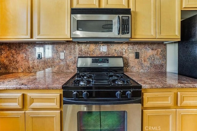 kitchen featuring light stone countertops, backsplash, and stainless steel appliances