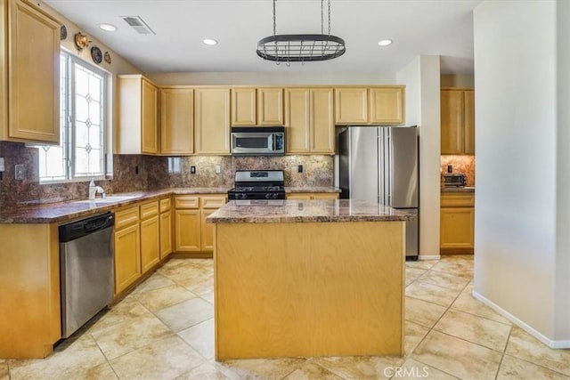 kitchen featuring light brown cabinetry, sink, stainless steel appliances, and a center island