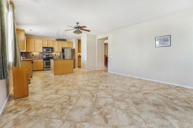 kitchen with a center island, backsplash, hanging light fixtures, ceiling fan, and stainless steel appliances