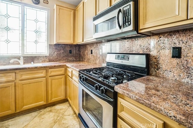 kitchen featuring sink, light stone countertops, light tile patterned floors, tasteful backsplash, and stainless steel appliances