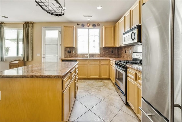 kitchen featuring tasteful backsplash, light stone countertops, a center island, and stainless steel appliances