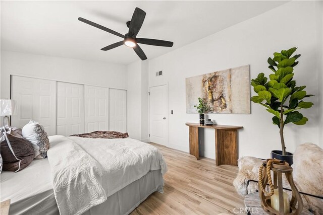 bedroom with a closet, light hardwood / wood-style flooring, and ceiling fan