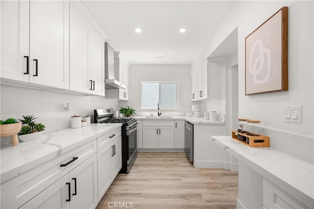 kitchen featuring light stone countertops, light hardwood / wood-style flooring, white cabinets, and stainless steel appliances