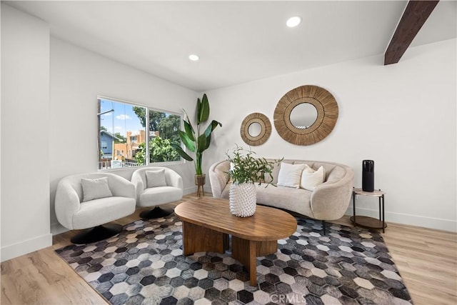 living room featuring beamed ceiling and light hardwood / wood-style floors