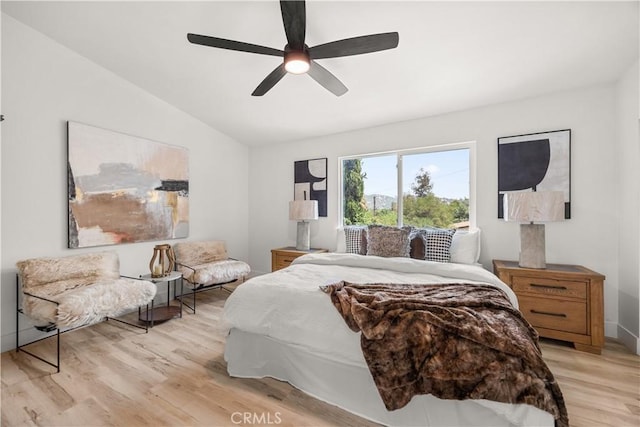 bedroom with ceiling fan, light hardwood / wood-style floors, and vaulted ceiling