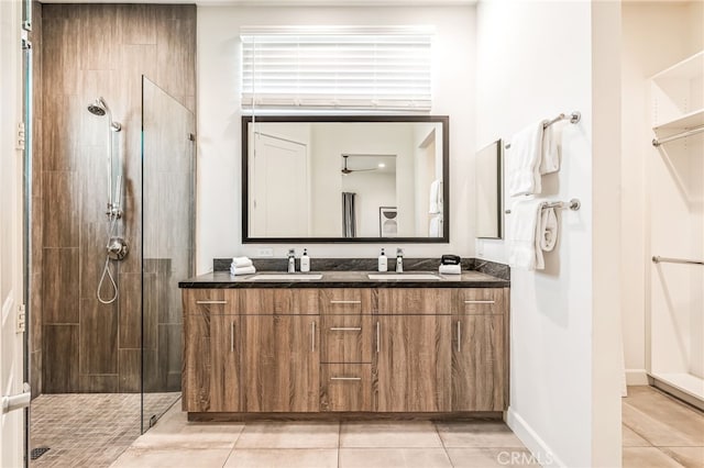 bathroom with tile patterned flooring, a tile shower, and vanity