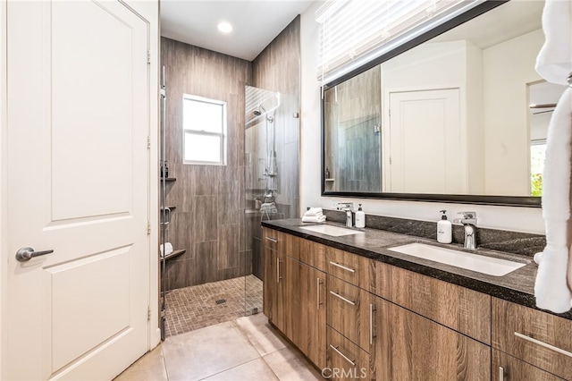 bathroom with tile patterned flooring, vanity, and tiled shower