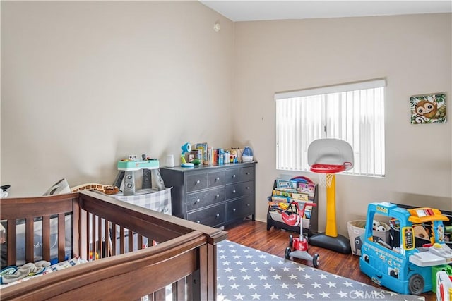 bedroom featuring lofted ceiling, a nursery area, and dark hardwood / wood-style floors