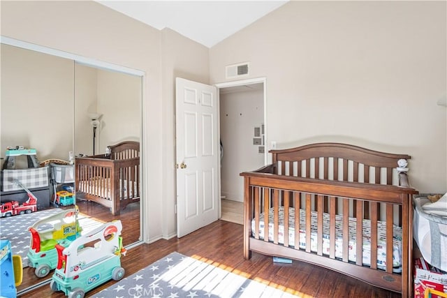 bedroom featuring hardwood / wood-style flooring, a nursery area, and lofted ceiling