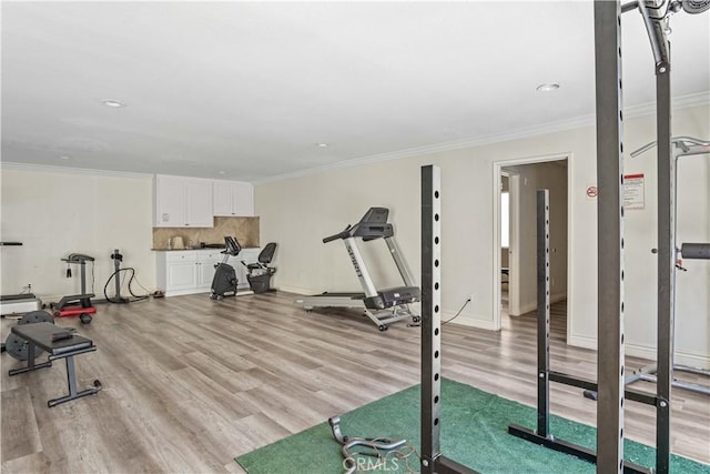 workout area with crown molding and light hardwood / wood-style flooring