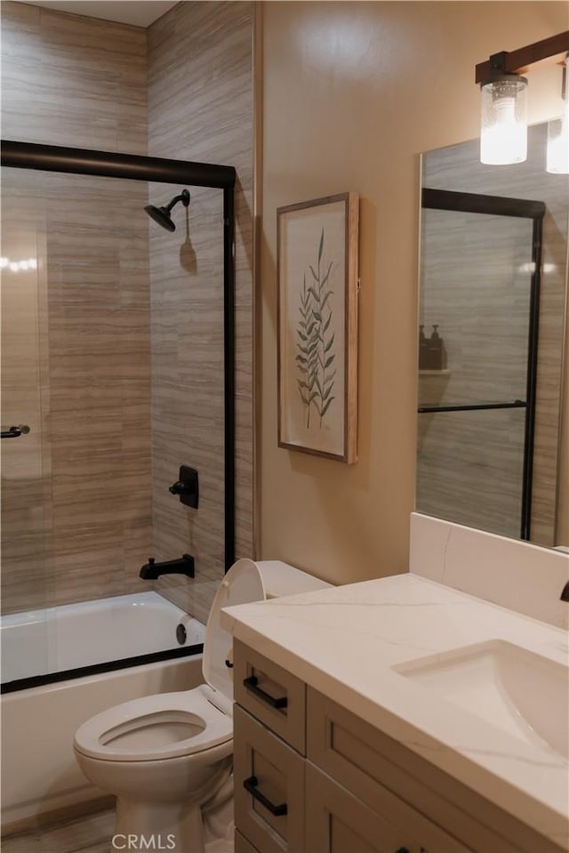 full bathroom with vanity, enclosed tub / shower combo, and toilet