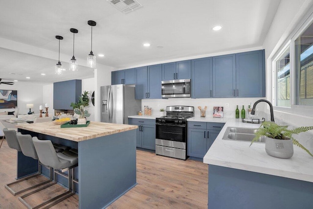 kitchen with a center island, appliances with stainless steel finishes, decorative light fixtures, light hardwood / wood-style floors, and a breakfast bar area