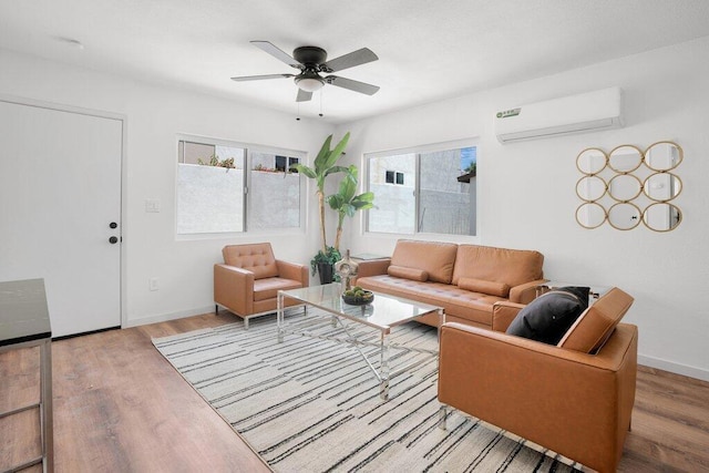 living room featuring a wall mounted air conditioner, light hardwood / wood-style floors, and ceiling fan