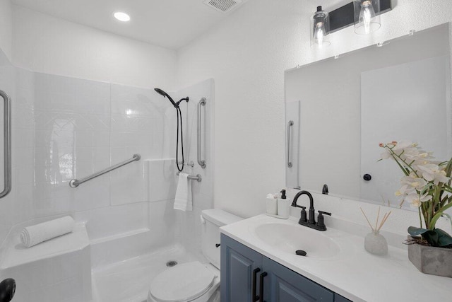 bathroom featuring tiled shower, vanity, and toilet