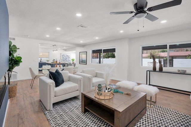 living room with light hardwood / wood-style flooring and ceiling fan with notable chandelier