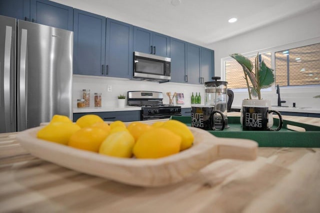 kitchen featuring appliances with stainless steel finishes, tasteful backsplash, and blue cabinets