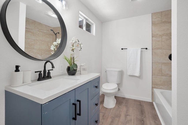 full bathroom with tiled shower / bath, vanity, wood-type flooring, and toilet