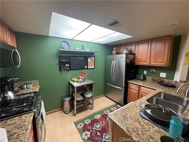 18223 Soledad Canyon Rd Unit 29, Canyon Country, CA 91387 - kitchen with stainless steel appliances, a sink, light wood-style floors, brown cabinets, and baseboards