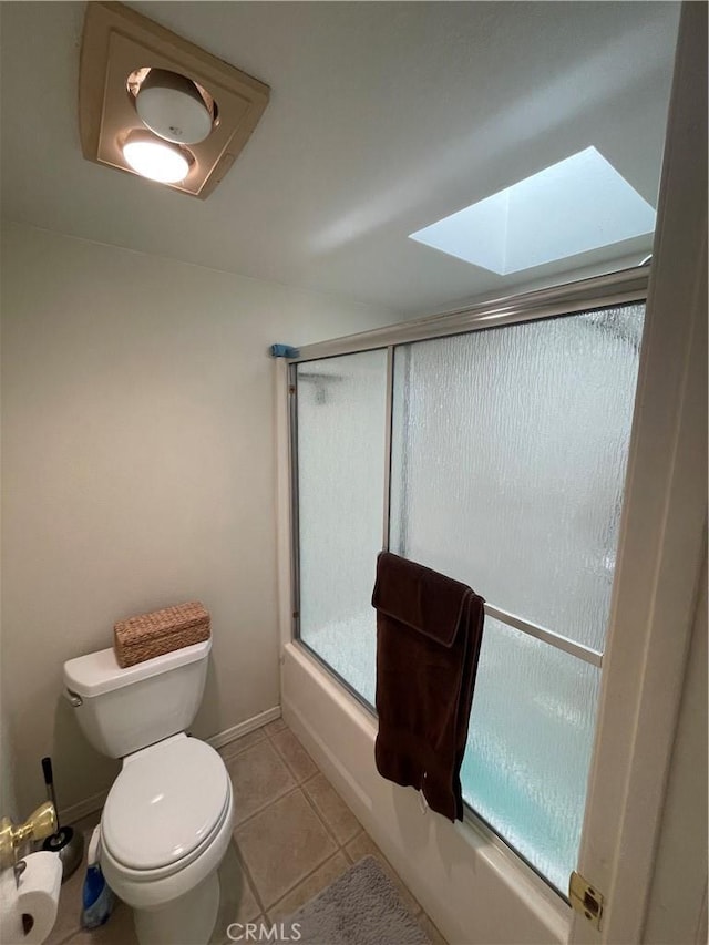 bathroom with toilet, a skylight, tile patterned floors, and bath / shower combo with glass door