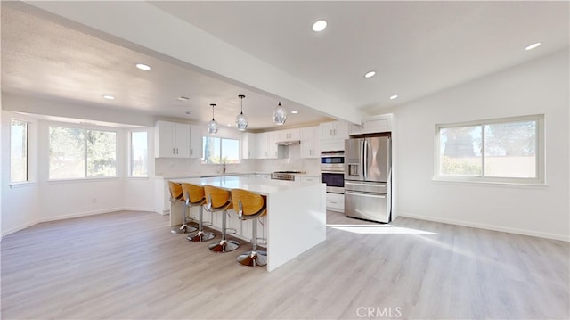 kitchen with white cabinets, a wealth of natural light, a kitchen island, and appliances with stainless steel finishes