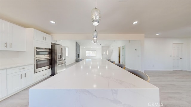 kitchen featuring white cabinets, pendant lighting, light hardwood / wood-style floors, and appliances with stainless steel finishes