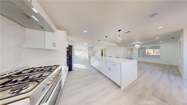 kitchen featuring stainless steel appliances, extractor fan, decorative light fixtures, light hardwood / wood-style floors, and white cabinets