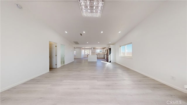 unfurnished living room featuring light wood-type flooring, high vaulted ceiling, and a chandelier