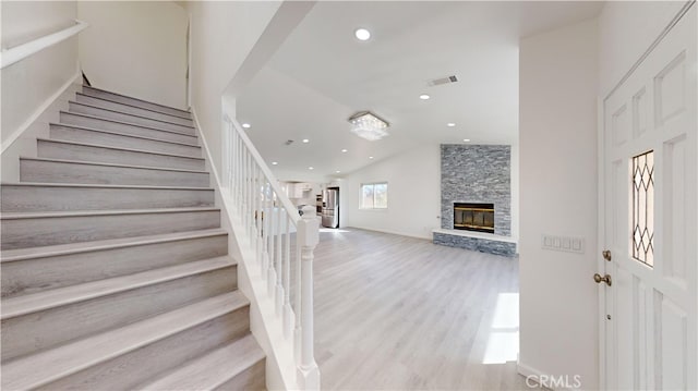 stairway featuring a fireplace, hardwood / wood-style flooring, and lofted ceiling