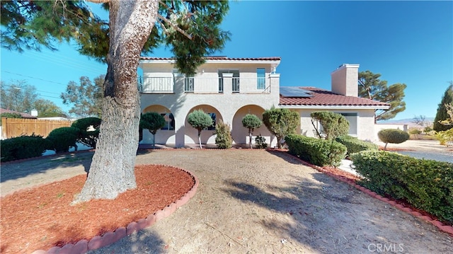 mediterranean / spanish-style home featuring solar panels and a balcony