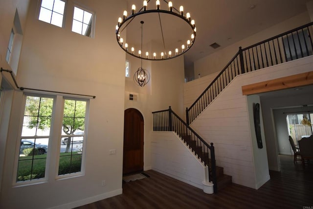 foyer with a towering ceiling, dark wood-type flooring, and an inviting chandelier