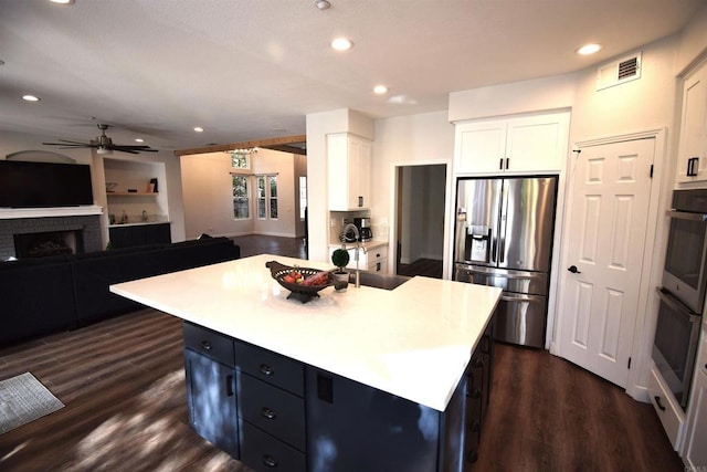 kitchen featuring a center island, stainless steel appliances, white cabinetry, and dark hardwood / wood-style floors