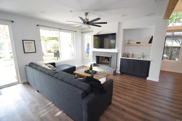 living room with a wealth of natural light, a fireplace, and dark wood-type flooring