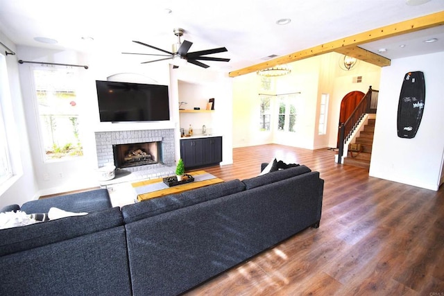 living room featuring ceiling fan, dark wood-type flooring, and a brick fireplace