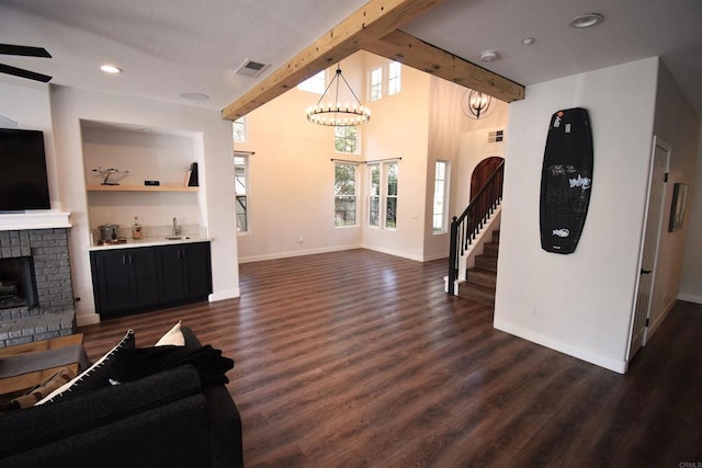 living room with beam ceiling, a brick fireplace, dark wood-type flooring, and sink