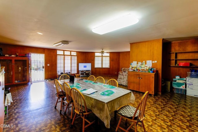 dining space featuring wood walls and ceiling fan